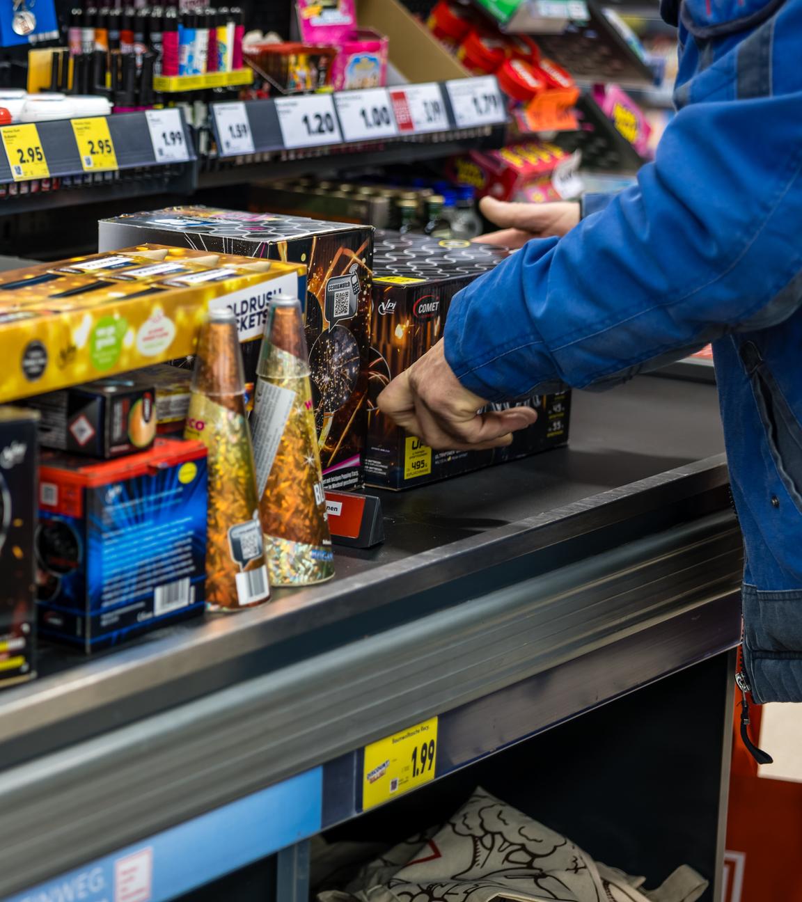  An der Kasse eines Supermarktes legt ein Kunde Feuerwerk auf das Kassenband.