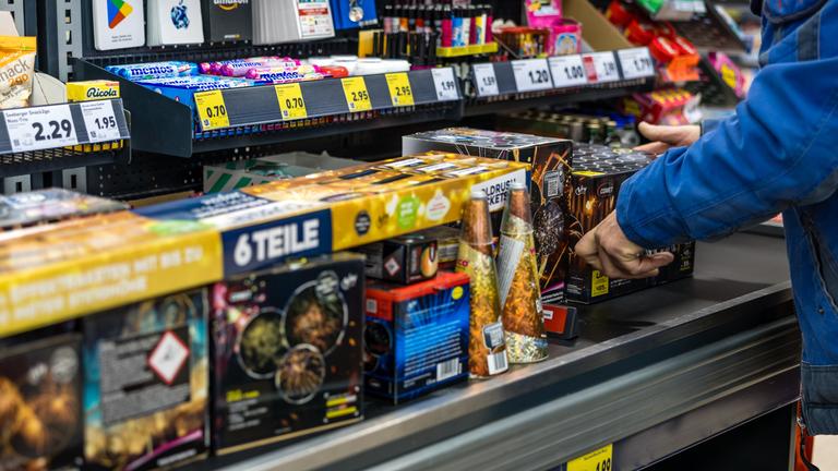  An der Kasse eines Supermarktes legt ein Kunde Feuerwerk auf das Kassenband.