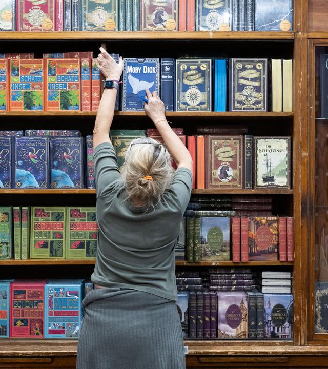 Bücher werden vor dem ersten Fachbesuchertag auf der Buchmesse auf einem Messestand einsortiert. 
