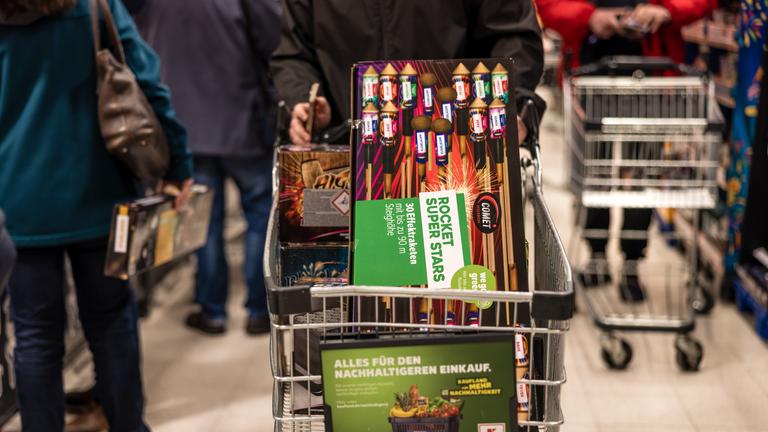 Ein Kunde fährt mit einem Einkaufswagen voller Feuerwerk durch einen Supermarkt.