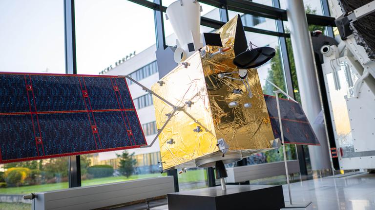 Modelle von Satelliten stehen im Firmengebäude des Raumfahrt- und Technologiekonzerns OHB. 