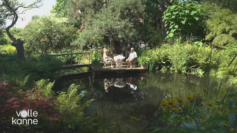 Zwei Menschen sitzen im Garten vor einem See