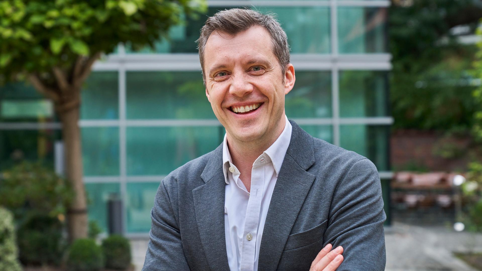 Stefan Drüssler, Geschäftsführer und Chief Operating Officer von UnternehmerTUM, blickt in einem grauen Anzug lachend in die Kamera.