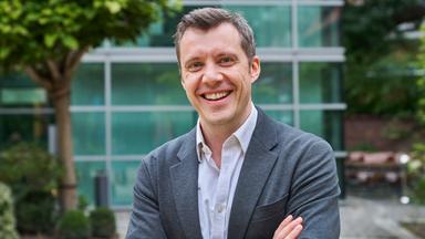 Stefan Drüssler, Geschäftsführer und Chief Operating Officer von UnternehmerTUM, blickt in einem grauen Anzug lachend in die Kamera.