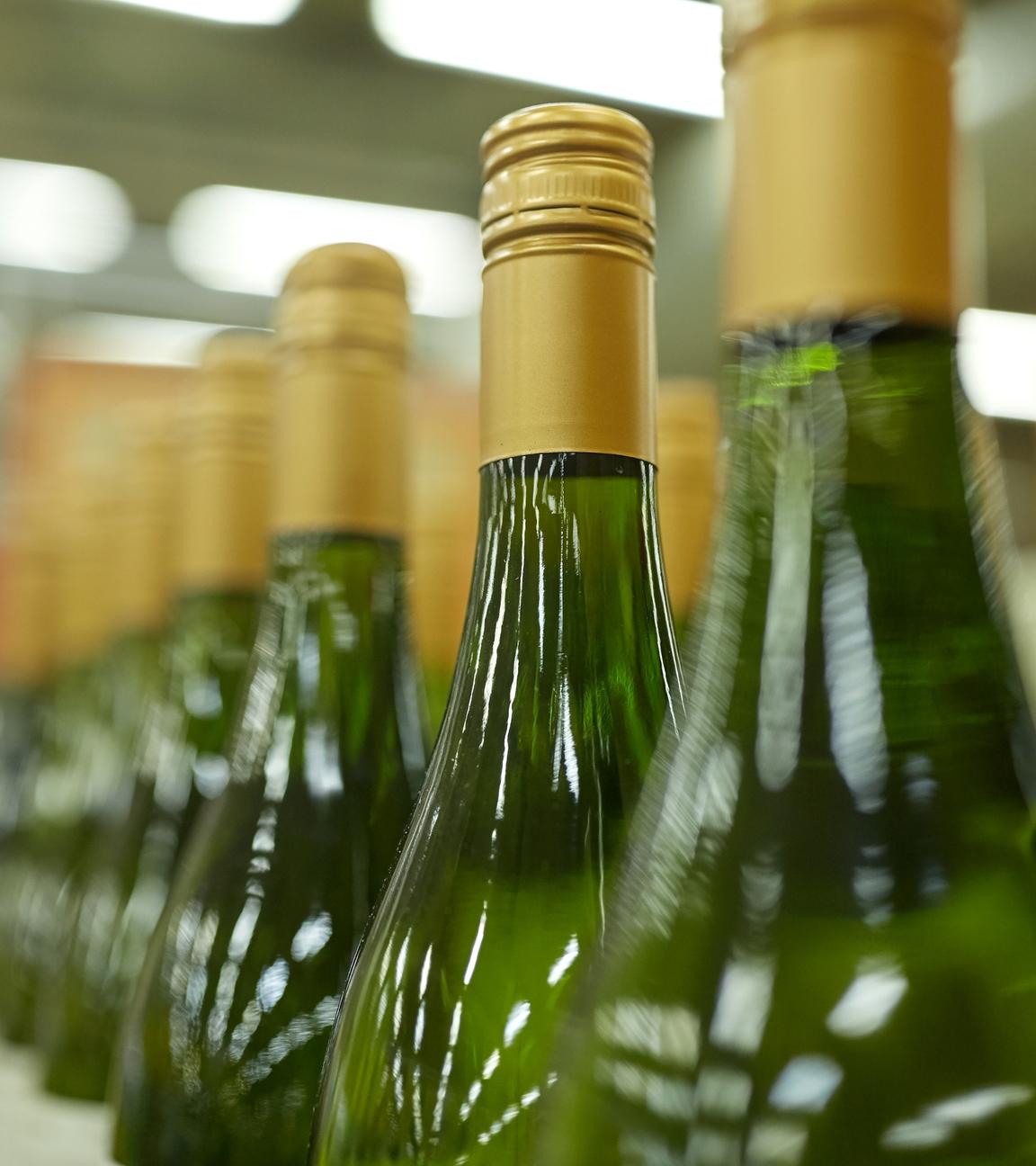 Weißweinflaschen stehen in einer Reihe eines Supermarktregals.