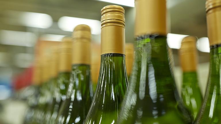 Weißweinflaschen stehen in einer Reihe eines Supermarktregals.