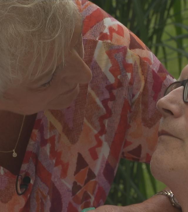 Eine Frau, die sich über ihren Mann beugt, der krank ist.