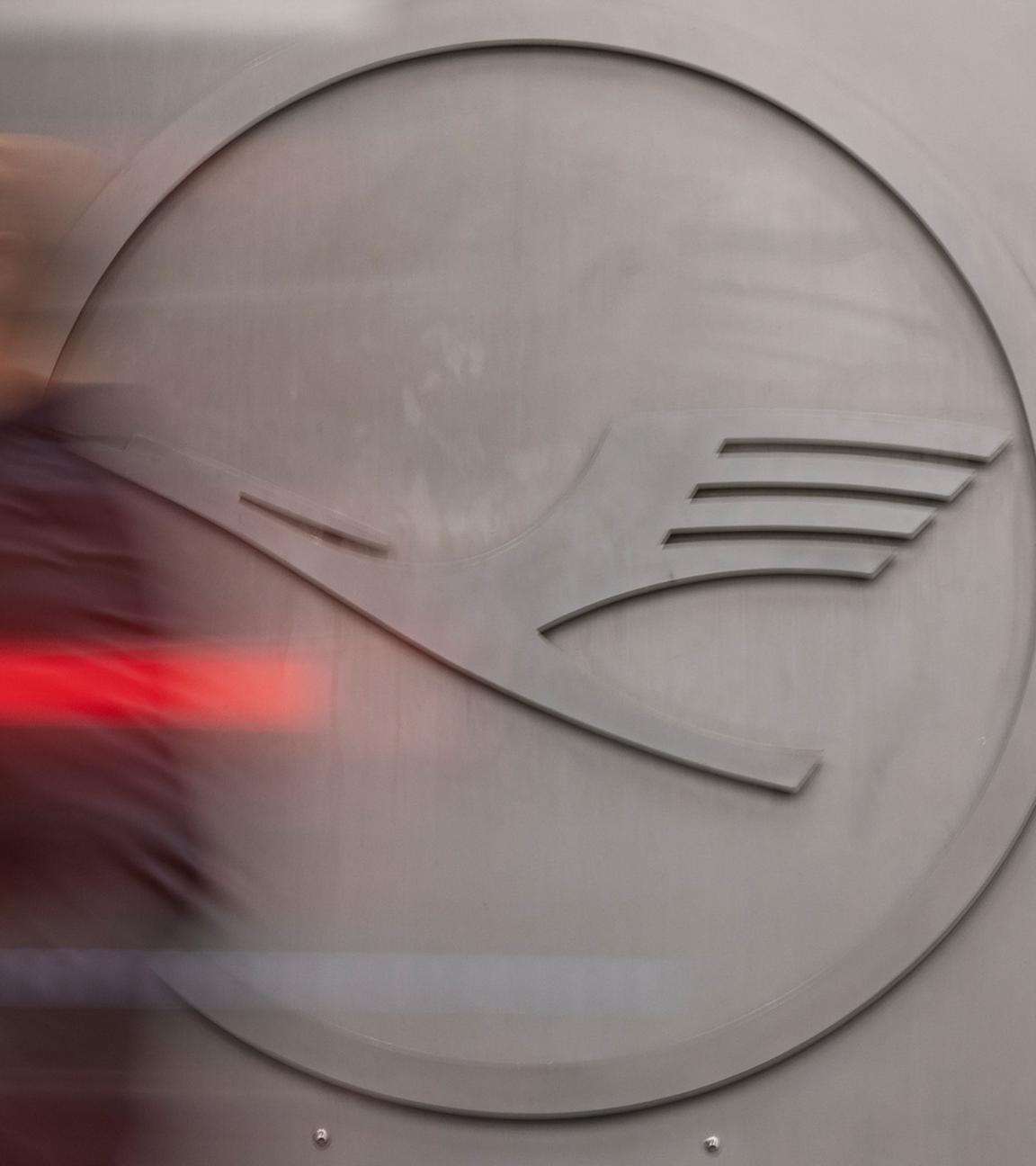 Ein Mann geht vor einem Lufthansa-Logo am Frankfurter Flughafen.