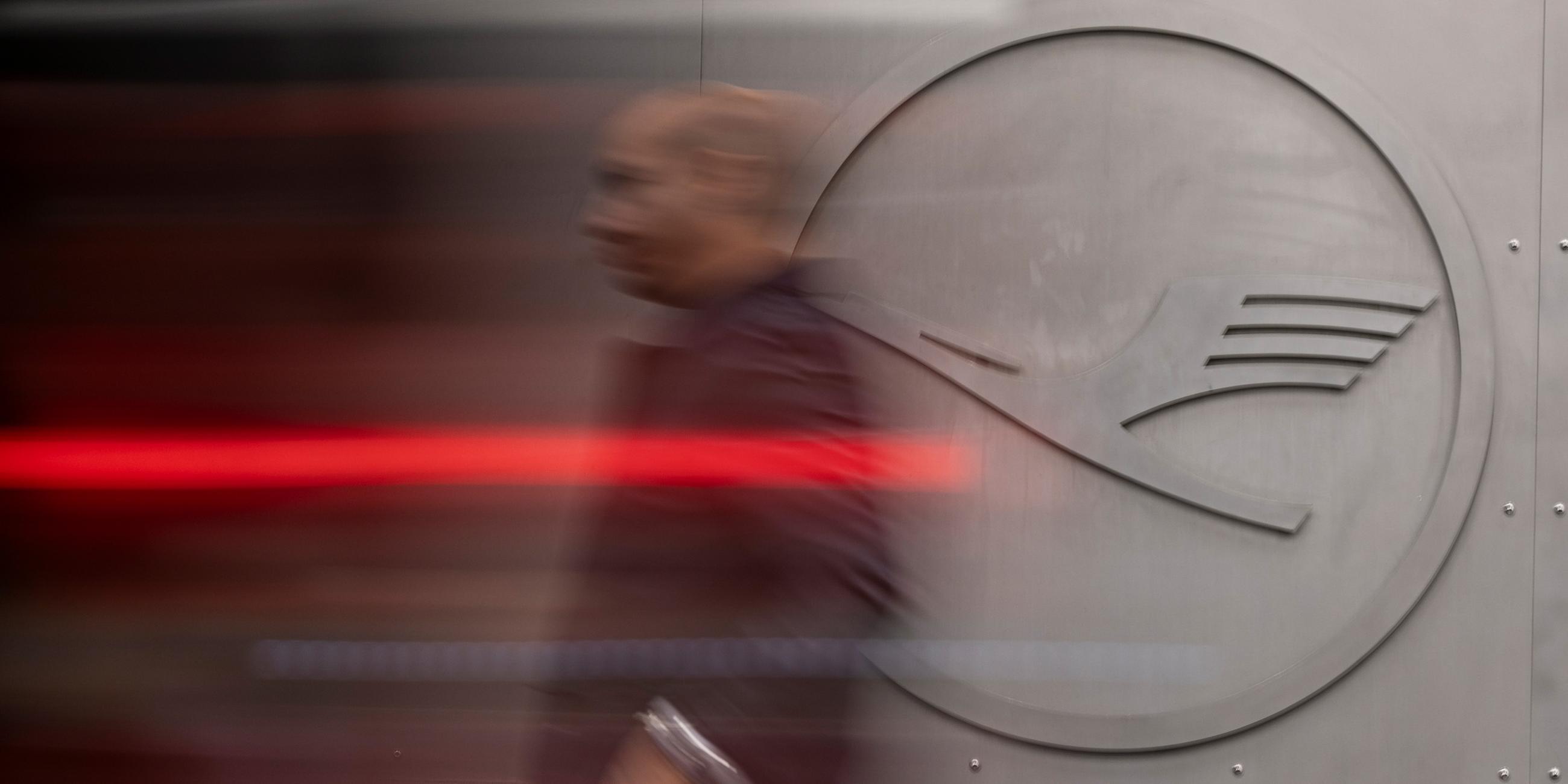 Ein Mann geht vor einem Lufthansa-Logo am Frankfurter Flughafen.
