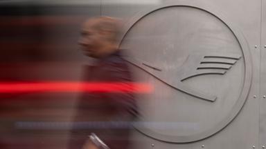 Ein Mann geht vor einem Lufthansa-Logo am Frankfurter Flughafen.