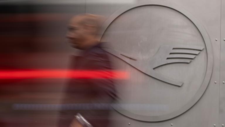 Ein Mann geht vor einem Lufthansa-Logo am Frankfurter Flughafen.