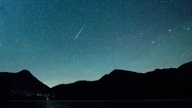 Bayern, Einsiedl: Eine Sternschnuppe leuchtet neben der Milchstraße am Himmel über dem Walchensee.