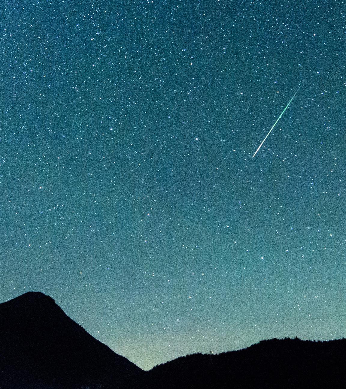 Eine Sternschnuppe leuchtet neben der Milchstraße am Himmel über dem Walchensee am 12.08.2018.
