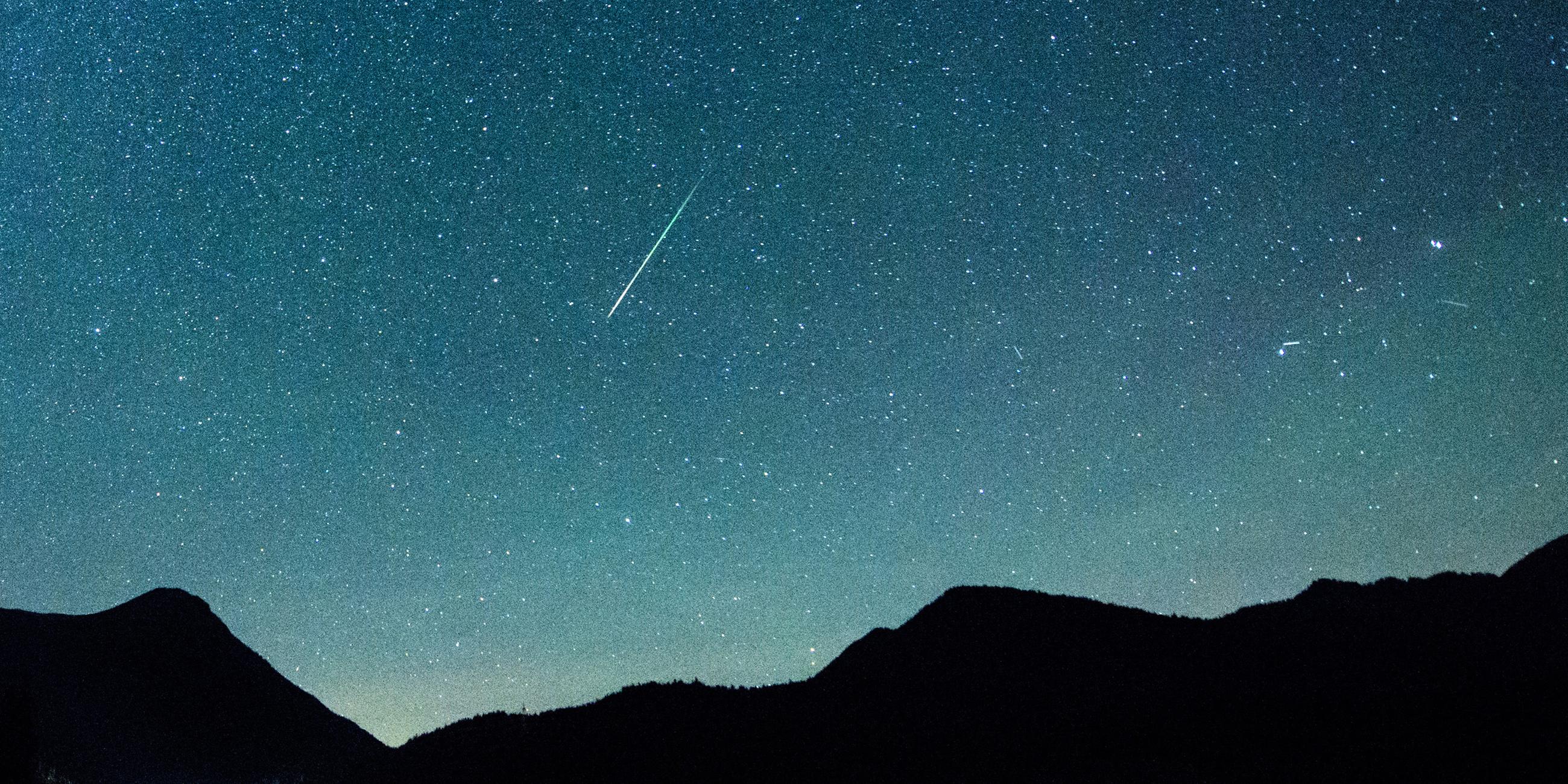 Eine Sternschnuppe leuchtet neben der Milchstraße am Himmel über dem Walchensee am 12.08.2018.