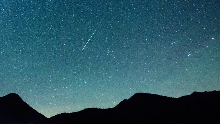 Eine Sternschnuppe leuchtet neben der Milchstraße am Himmel über dem Walchensee am 12.08.2018.