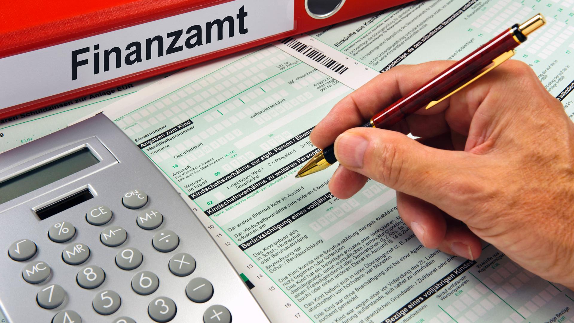 Symbolbild: Eine Hand mit Kugelschreiber über einem Formular für das Finanzamt