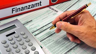 Symbolbild: Eine Hand mit Kugelschreiber über einem Formular für das Finanzamt
