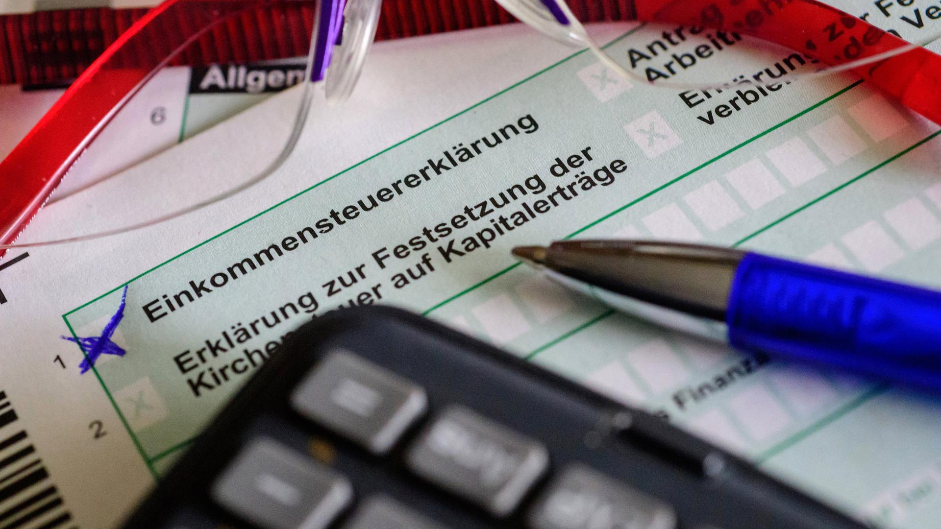 Steuerformulare sowie Brille, Stift und Taschenrechner liegen auf einem Tisch. (Symbolbild)