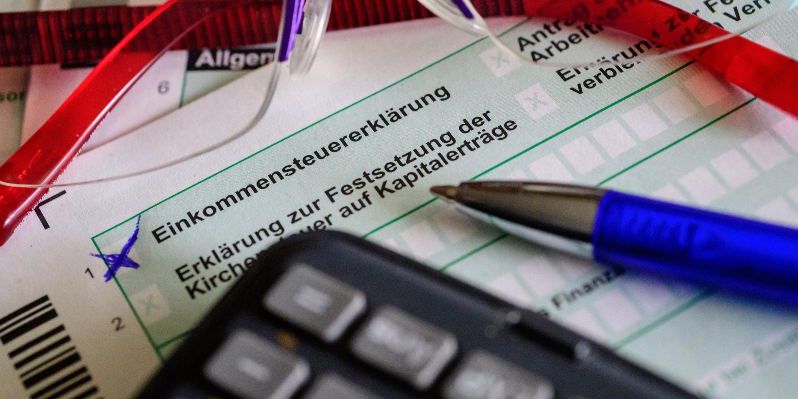 Steuerformulare sowie Brille, Stift und Taschenrechner liegen auf einem Tisch. (Symbolbild)