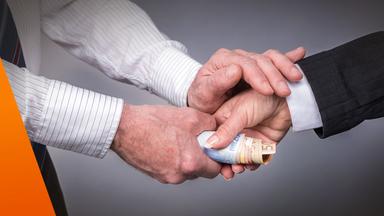 Handschütteln: Dabei übergibt eine Hand der anderen mehrere Geldscheine