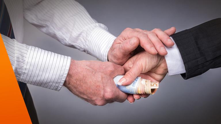 Handschütteln: Dabei übergibt eine Hand der anderen mehrere Geldscheine