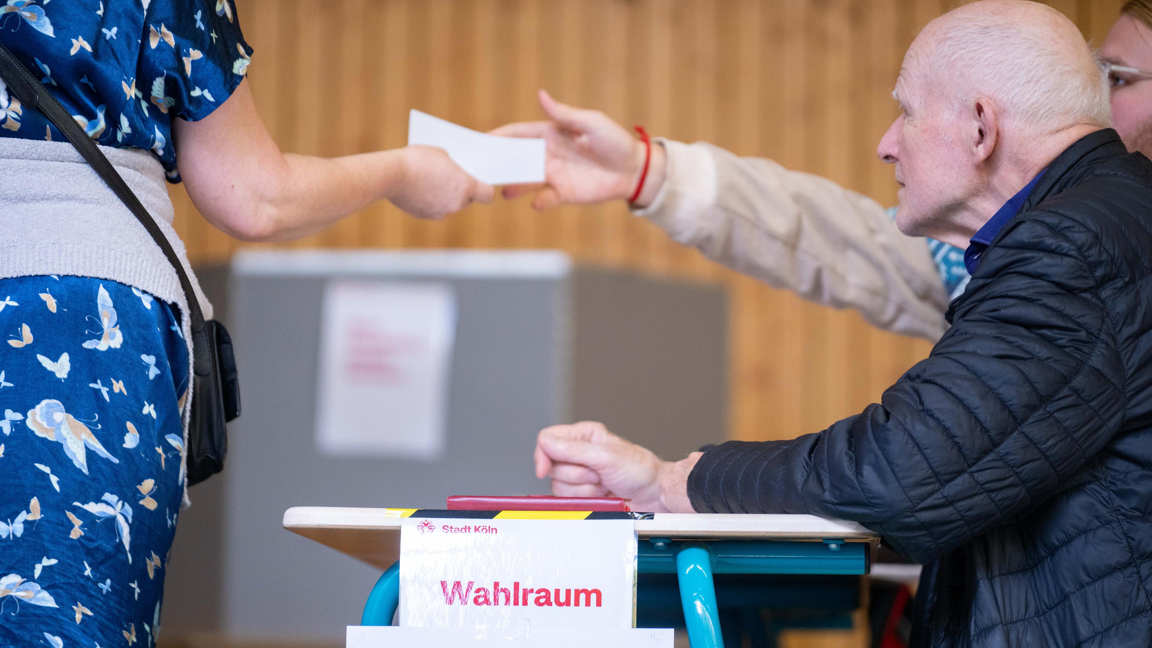 Ein Wahlhelfer übergibt ein einen Stimmzettel zur Stichwahl im Wahlraum 