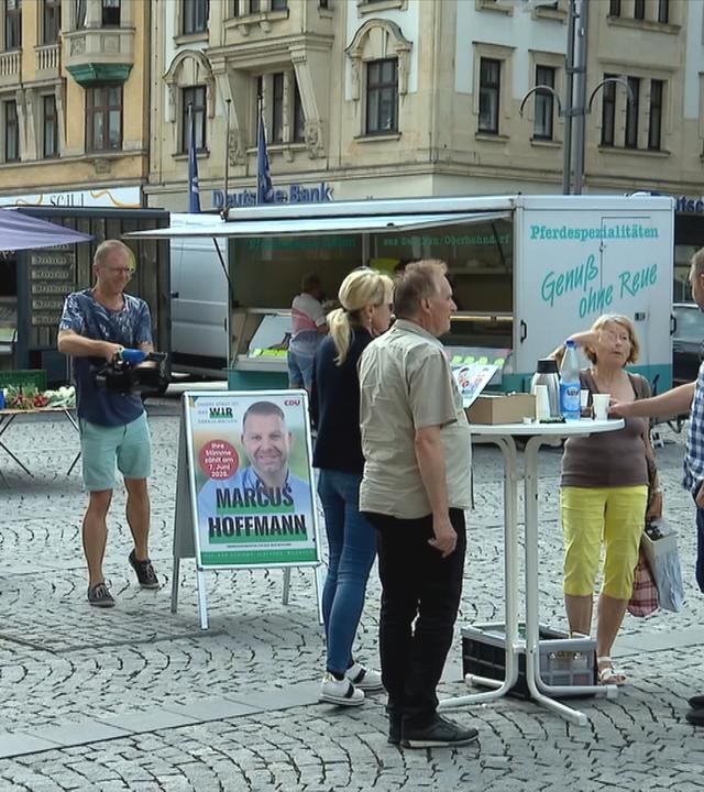 Markt mit Menschen, auf dem Wahlplakat von Marcus Hoffmann (CDU) steht