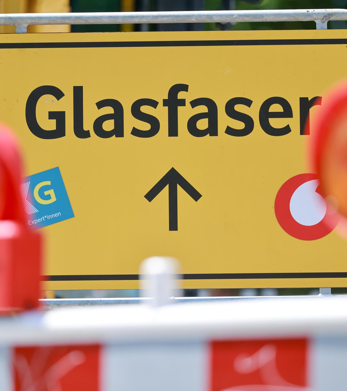 Ein gelbes Schild mit der Schrift "Glasfaserausbau". Um das Schild herum stehen Baustellenabkrezungen.