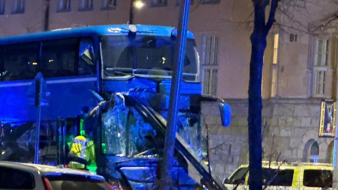 Zu sehen ist der zerstörte Bus aus dem Busunfall in Stockholm, bei dem mehrere Menschen verstorben sind. Polizeikräfte untersuchen den Unfallort. .