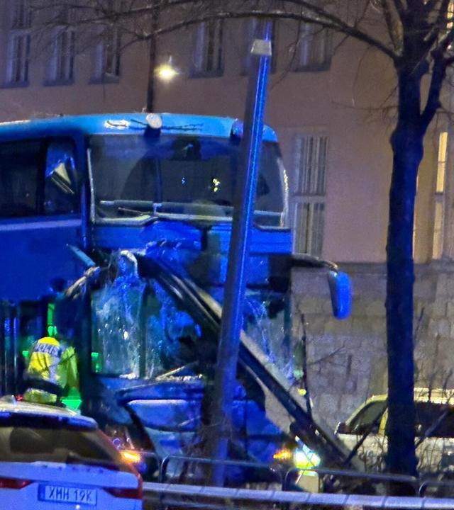 Zu sehen ist der zerstörte Bus aus dem Busunfall in Stockholm, bei dem mehrere Menschen verstorben sind. Polizeikräfte untersuchen den Unfallort. .