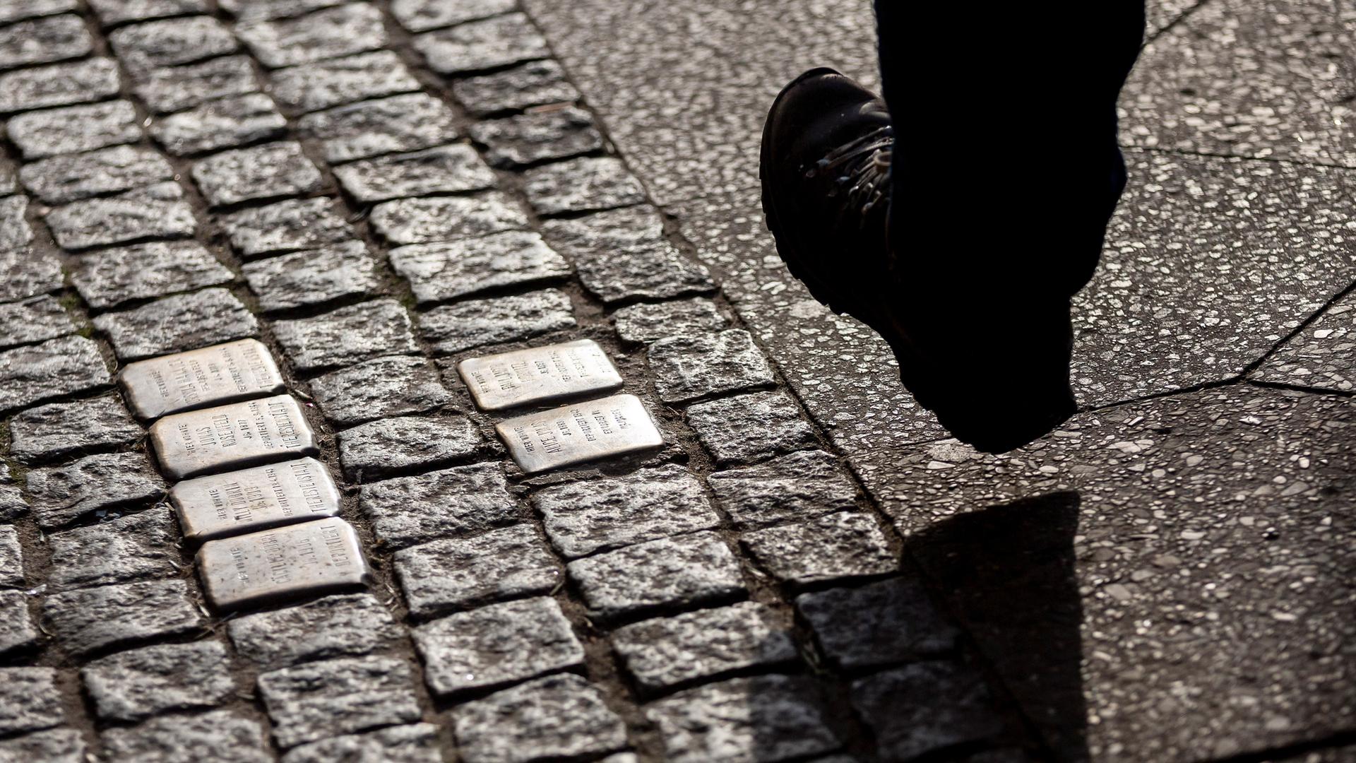 Ein Mann geht an Stolpersteinen vorbei