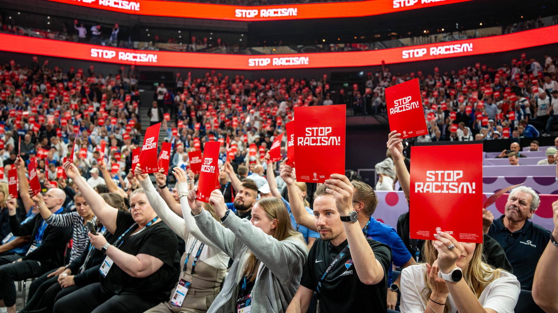 Basketball-EM, Finnland - Deutschland. Die Zuschauer in der Halle halten Rote Karten mit der Aufschrift «Stop Racism» in die Höhe