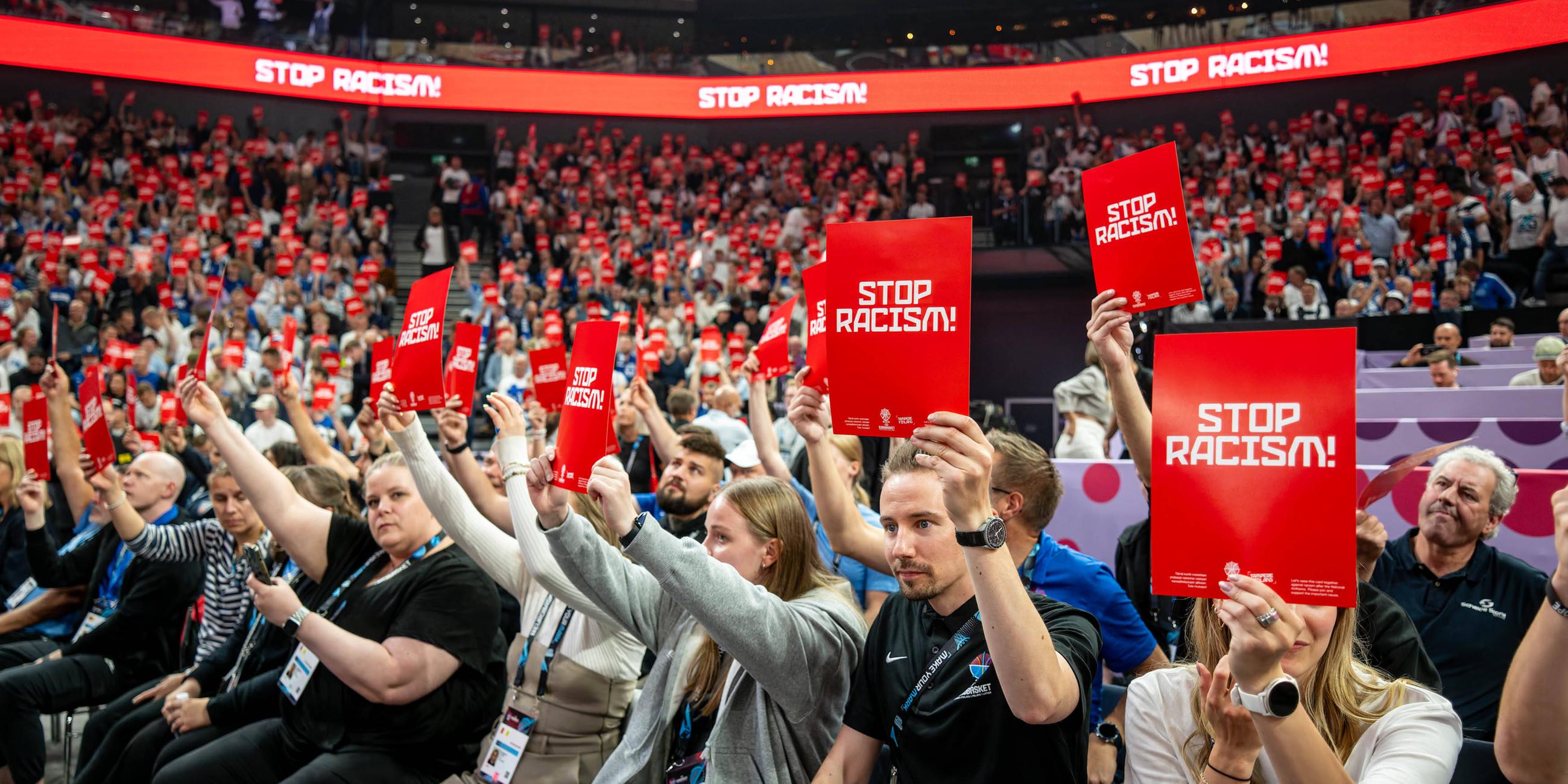 Basketball-EM, Finnland - Deutschland. Die Zuschauer in der Halle halten Rote Karten mit der Aufschrift «Stop Racism» in die Höhe