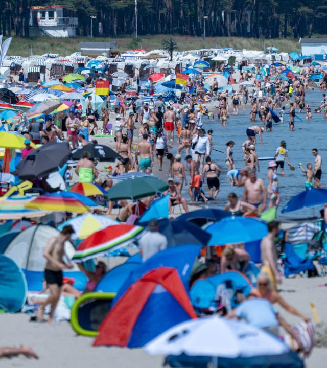 Ein voller Strand mit vielen Menschen.