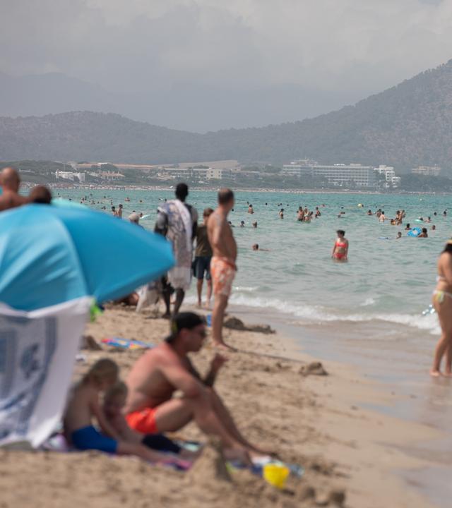 Touristen und Einheimische entspannen sich am Strand von Can Picafort und suchen Abkühlung im Wasser an der Nordküste von Mallorca.