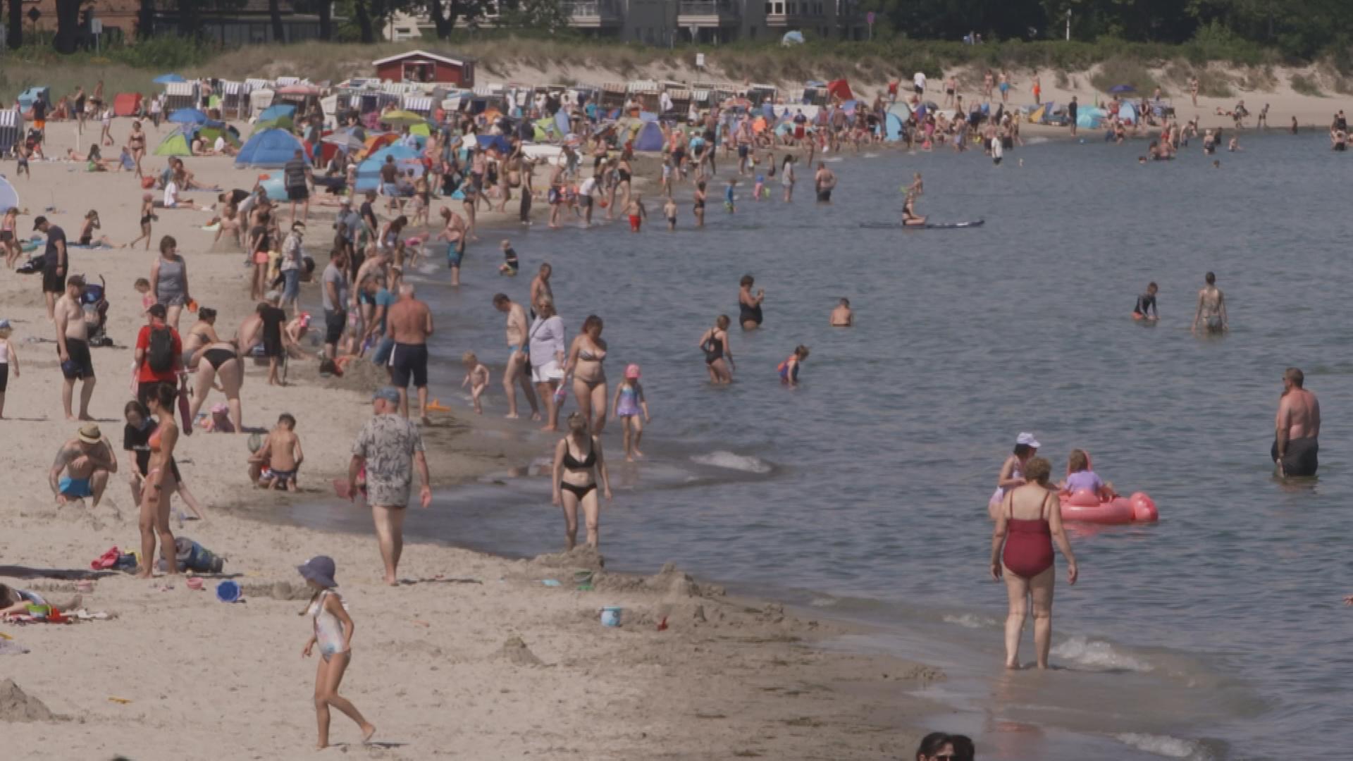 Auf dem Bild ist ein Strand voller Touristen zu sehen.