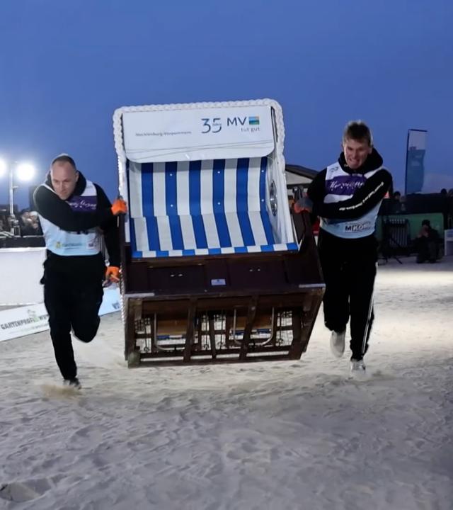 Zwei Männer tragen einen Strandkorb über die 20 Meter lange Laufstrecke.