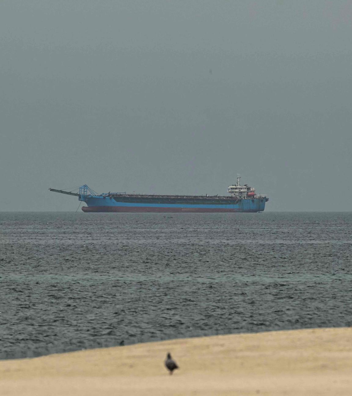 Ein Schiff im Persischen Golf vor der Küste von Sharjah, vorne ist nch ein Stück Strand zu sehen.