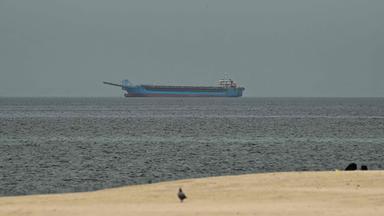 Ein Schiff im Persischen Golf vor der Küste von Sharjah, vorne ist nch ein Stück Strand zu sehen.