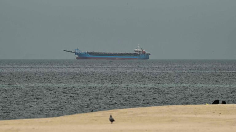 Ein Schiff im Persischen Golf vor der Küste von Sharjah, vorne ist nch ein Stück Strand zu sehen.