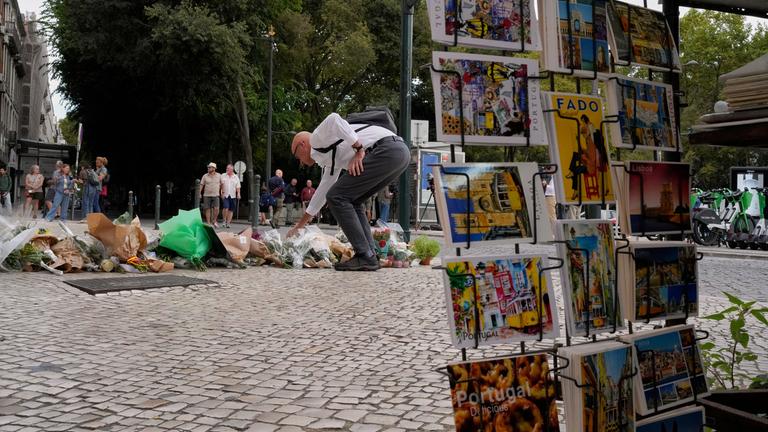 Ein Mann legt Blumen nieder in der Nähe des Unfallorts einer entgleisten und verunglückten Standseilbahn.