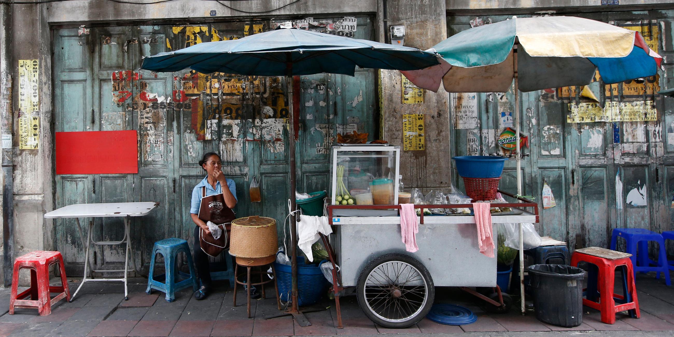 Frau wartet an einem Straßenstand in Bangkok