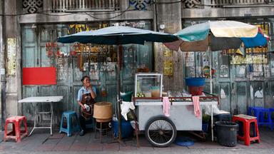 Frau wartet an einem Straßenstand in Bangkok