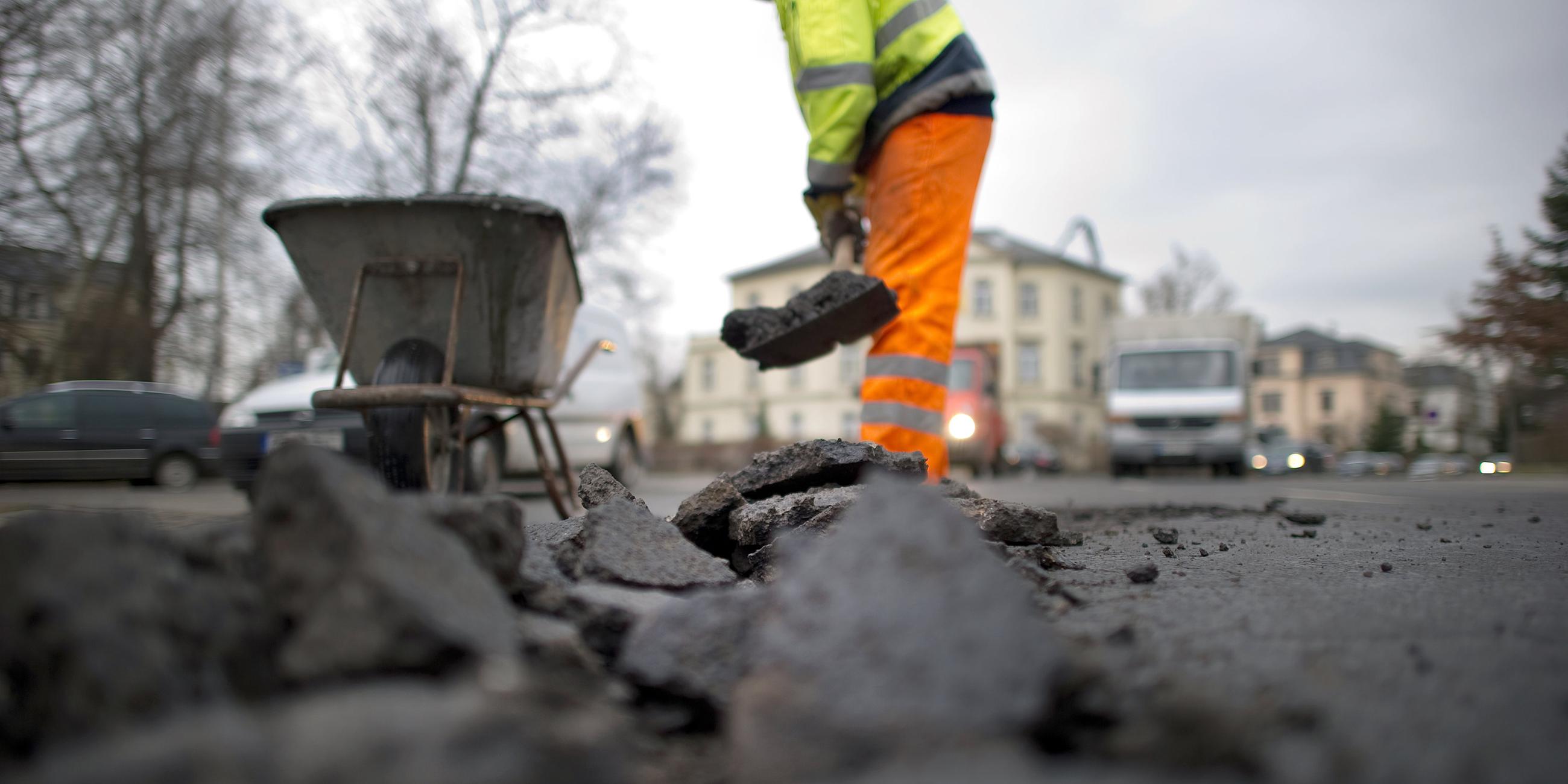 Ein Mitarbeiter einer Straßenbaufirma beseitigt in Dresden Straßenschäden