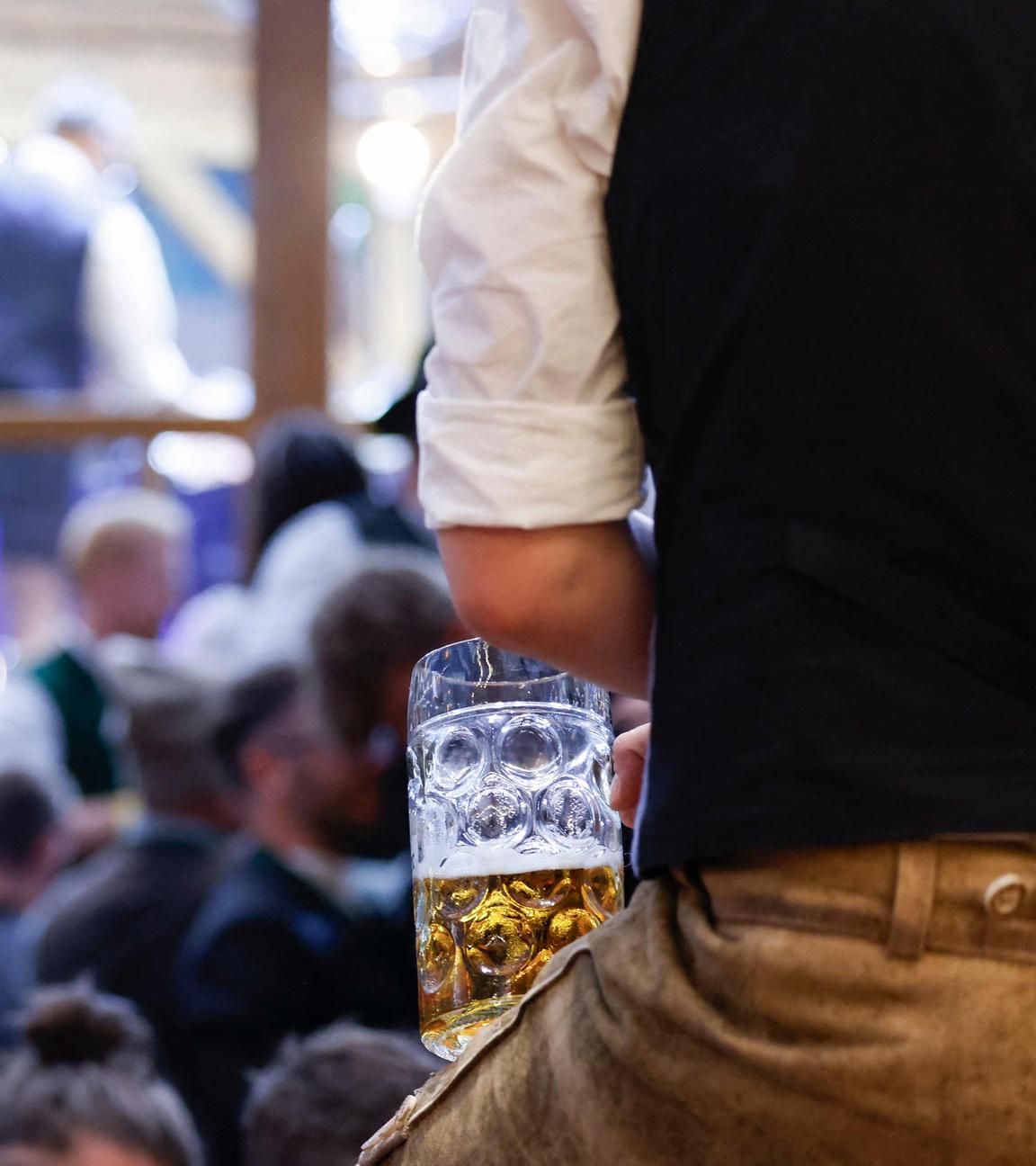 Ein Mann in Lederhosen blickt über die Besucher eines Zeltes auf dem Oktoberfest in München am 23.09.2025.