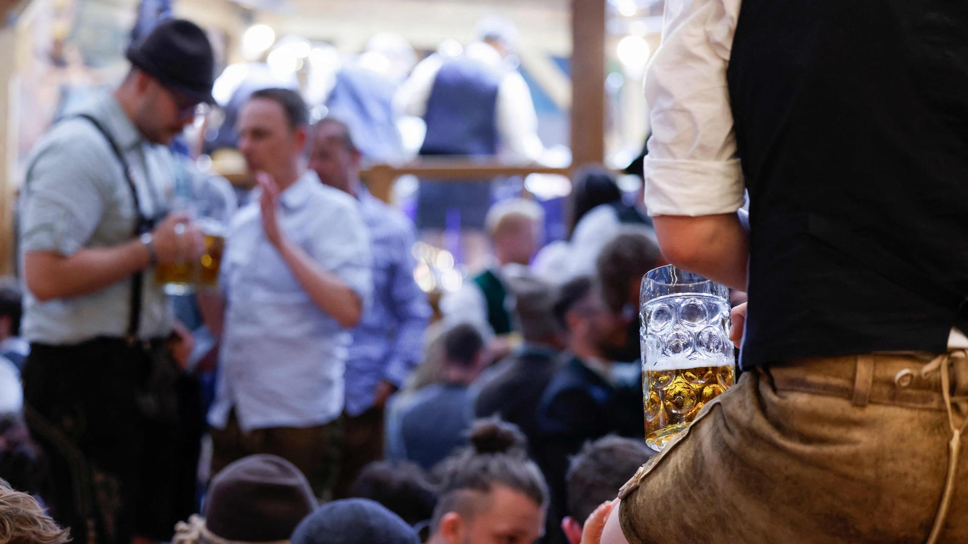 Ein Mann in Lederhosen blickt über die Besucher eines Zeltes auf dem Oktoberfest in München am 23.09.2025.