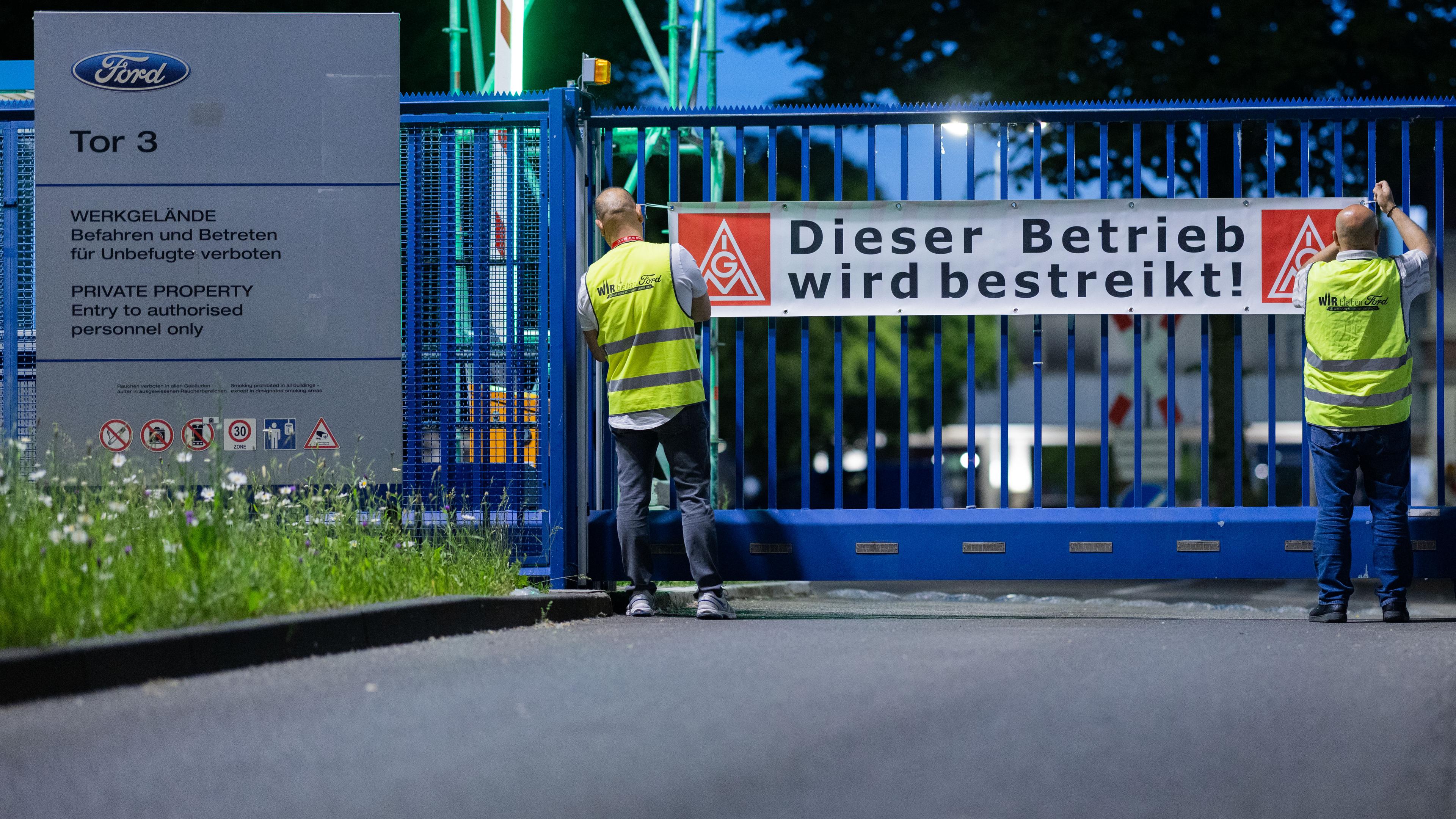 Mitarbeiter bringen beim ersten Streik in der Geschichte der Kölner Ford-Werke ein Banner vor dem Haupttor 3 an mit der Aufschrift "Dieser Betrieb wird bestreikt!".