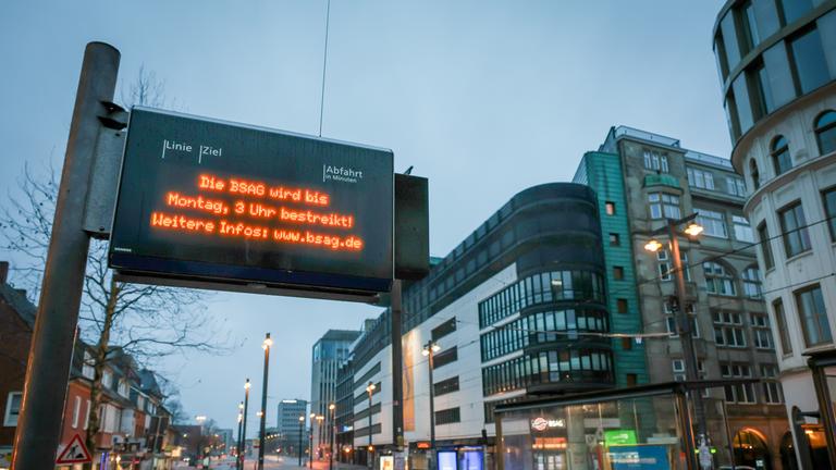 Eine Anzeigetafel weist an der Haltestelle der Bremer Straßenbahn AG (BSAG) am PNV-Knotenpunkt Domsheide im Morgengrauen auf einen Streik hin. 