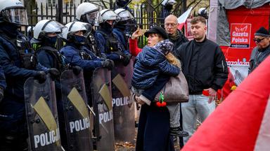 Eine Frau, die ein Kind trägt, steht vor Polizisten in Polizeiausrüstung, während sich Demonstranten vor dem Hauptsitz des polnischen Verfassungsgerichts in Warschau versammeln, nachdem die Polizei am 31. Oktober 2026 den Zugang zum Gebäude blockiert hatte.