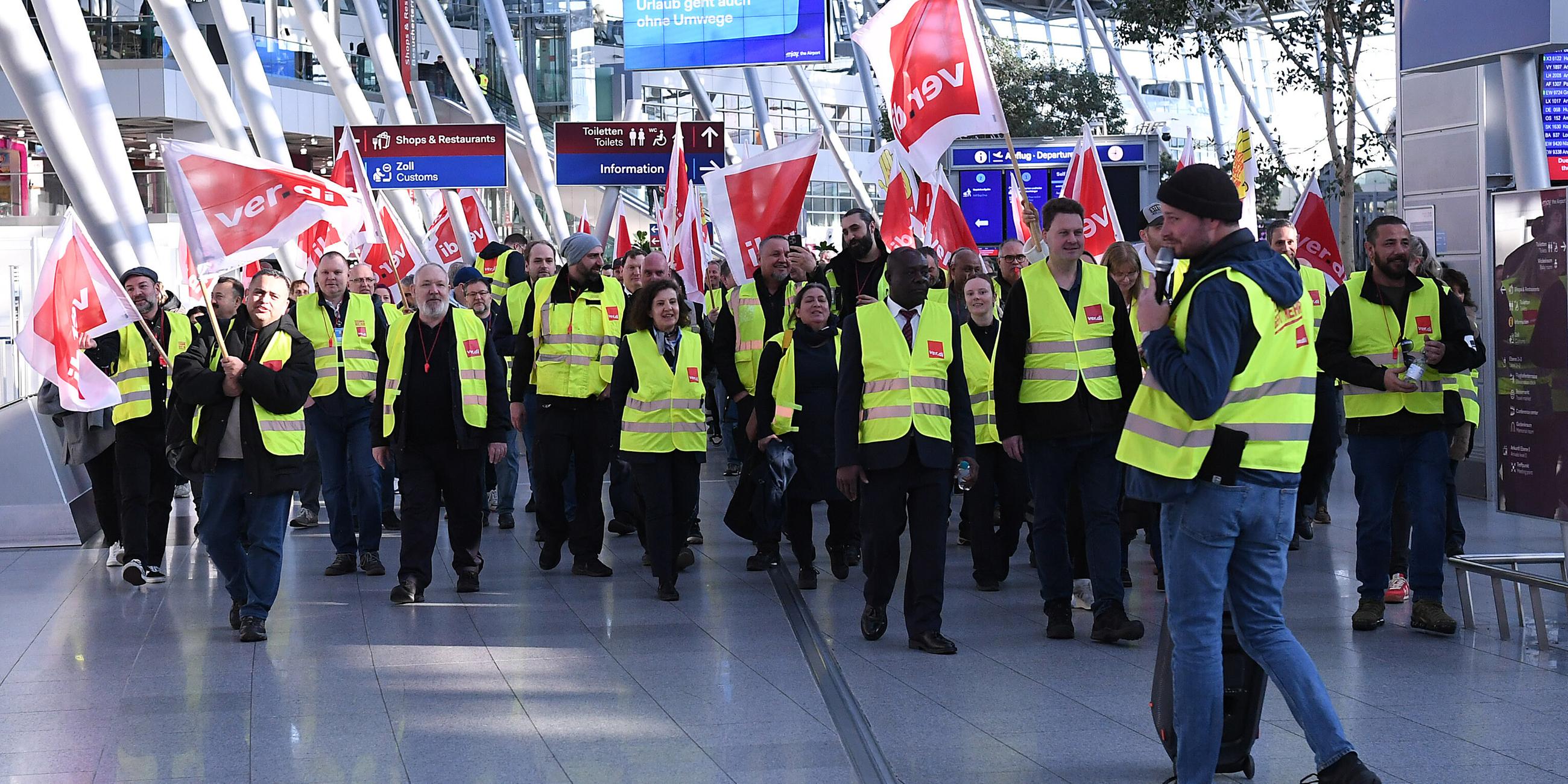 Warnstreik der Beschaeftigten im Luftsicherheitsbereich am 10.03.2025 am Flughafen Duesseldorf in Duesseldorf Mitglieder der Gewerkschaft Verdi laufen mit Fahnen bei einem Streik in einem Teminal des Duesseldorfer Flughafens. Die Gewerkschaft Verdi hat die Beschaeftigten des oeffentlichen Dienstes und der Bodenverkehrsdienste fuer Montag zu einem 24-stuendigen Warnstreik an 13 Flughaefen aufgerufen. 